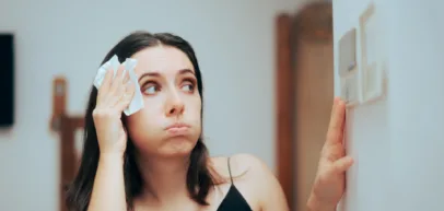 woman sweating and turning on ac despite high electric bill